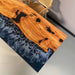 Wooden table with black resin inlay on a dark blue epoxy resin surface