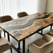 Handcrafted walnut dining table with black resin river placed in a modern minimalist home.