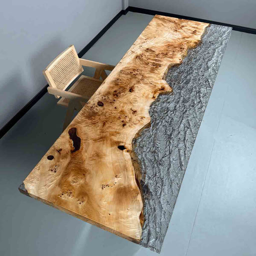 Wooden dining table with a river-like design on a gray floor.