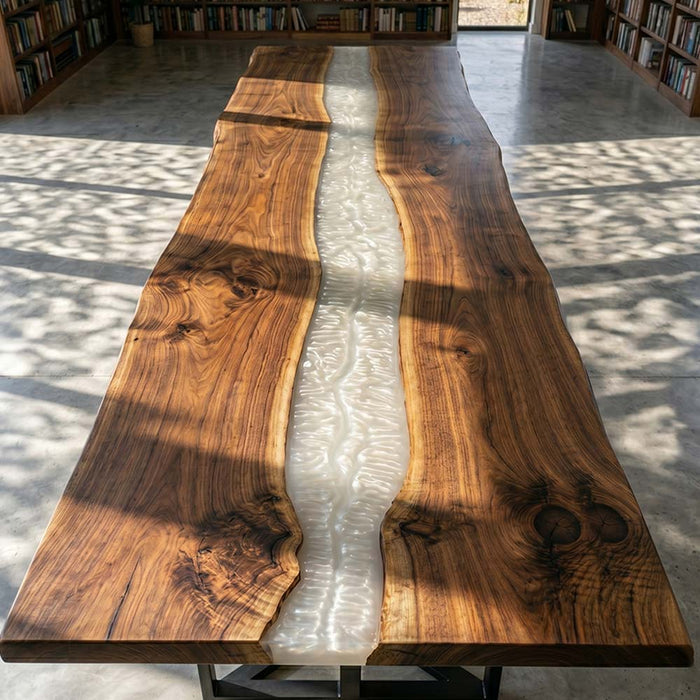 Wooden table with a river of white material running through it, in a room with books and a window.