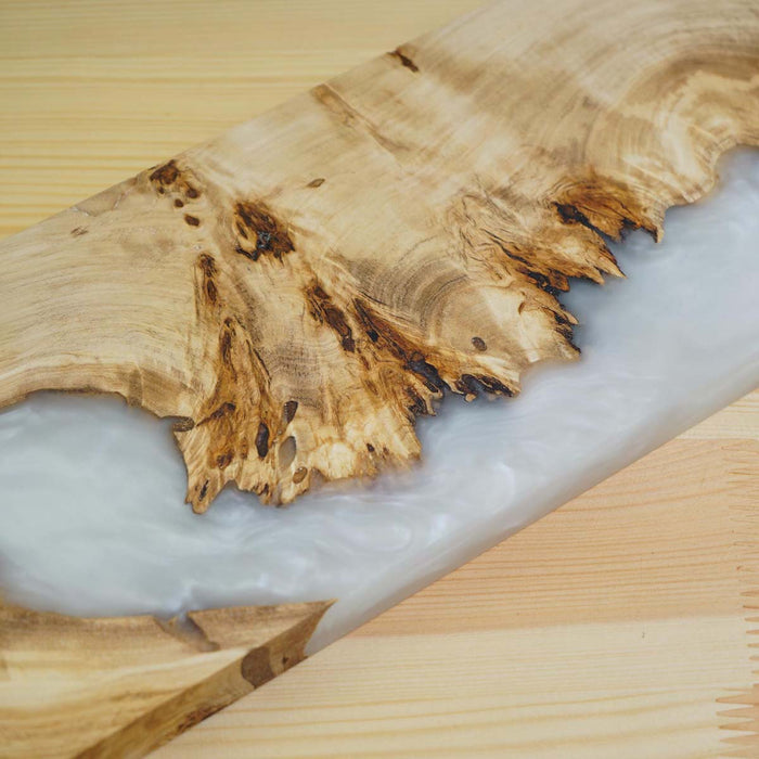 Wooden cutting board with a white resin finish on a wooden surface
