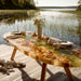 Wooden table with a lakeside view, set for a meal with plates, cups, and flowers.