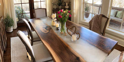 Dining room with a long wooden table set for a meal, featuring candles and a vase of flowers.