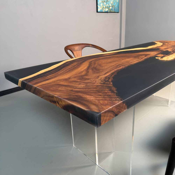 Dining table with wooden surface and black resin edge, clear legs on a gray background