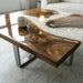 Brushed stainless steel geometric legs supporting a heavy solid wood and epoxy resin tabletop.