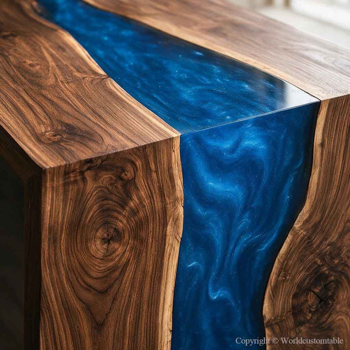 A close-up of a live-edge wooden table featuring rich brown wood grain and a vibrant, glossy blue resin inlay that flows down the center.