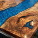 Close-up of a custom live-edge wooden table featuring dramatic swirling natural wood grain and bright blue resin channels.