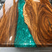 Green epoxy river table combining natural walnut slabs with modern resin artistry to create a unique live edge furniture piece.