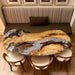 Custom golden camphor wood dining table featuring a unique ice crack epoxy river design and glossy resin finish.