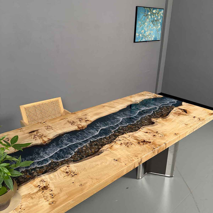 Wooden table with embedded blue river design in a room with a plant and wall art.