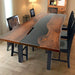 A sleek epoxy resin wood dining table with a dark wood grain and a flowing black epoxy resin river 