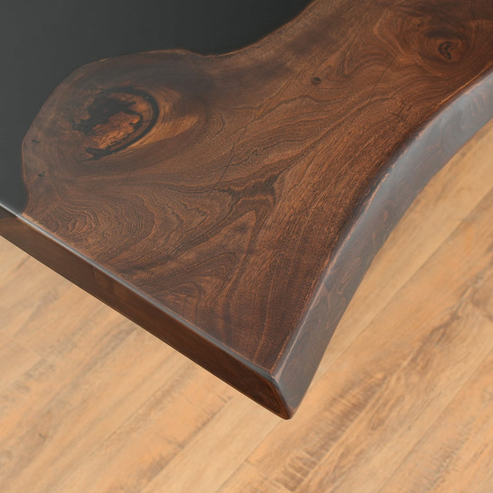 A sleek epoxy resin wood table with a dark wood grain and a flowing black epoxy resin river.