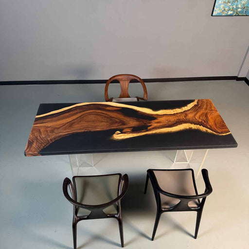 Wooden dining table with black surface and three chairs in a minimalistic setting.