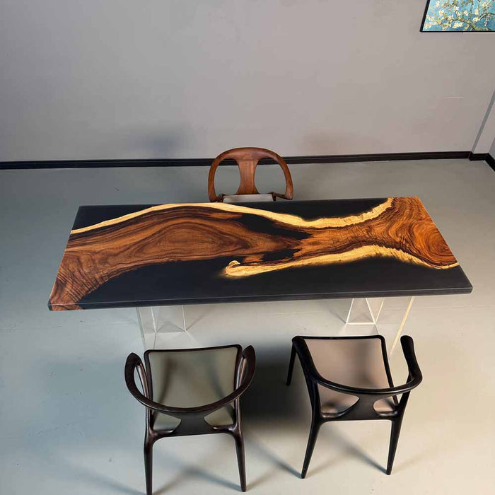 Wooden dining table with black surface and three chairs in a minimalistic setting.