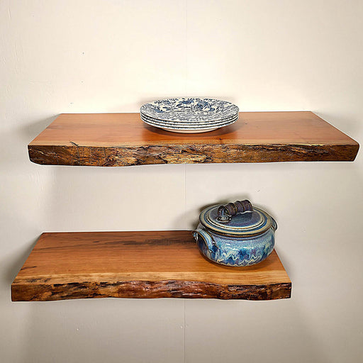 Two wooden shelves with decorative plates and a pot on a plain wall.