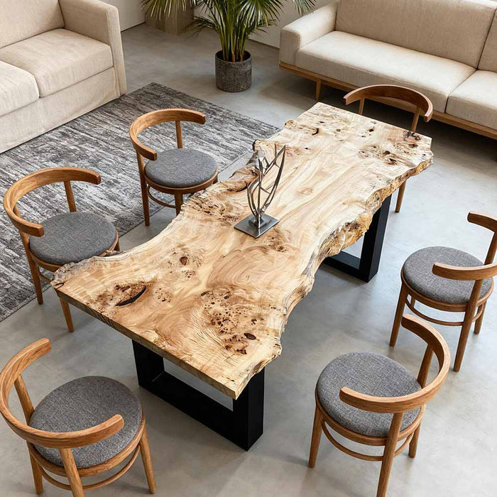 Wooden dining table with natural finish surrounded by matching chairs in a modern living room.
