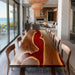 Dining room with a unique wooden table featuring a red and gold design, surrounded by chairs.
