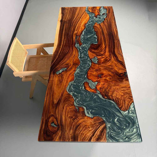 Wooden table with a unique design featuring a river-like pattern, accompanied by a chair.