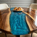 Close up of the live edge black walnut wood slabs joined by a glowing blue resin flow.