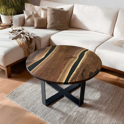 Round wooden coffee table with black metal legs in a living room setting.