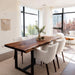 Dining room with a wooden table and white chairs near large windows.