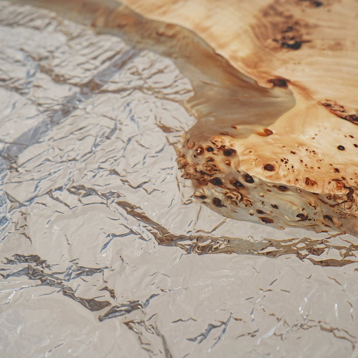 Modern dining table with transparent epoxy and natural wood base.