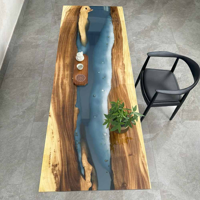 Wooden table with blue resin inlay and black chair on gray floor