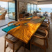 Dining area with a large wooden table and chairs in a modern home setting with ocean view.
