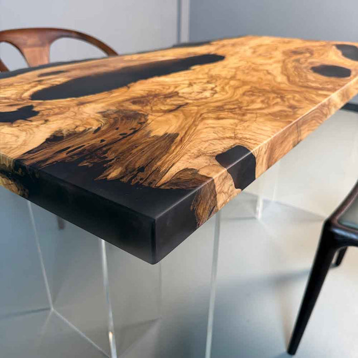 Wooden table with black resin finish and clear legs on a white background
