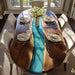 Dining table with wooden top and blue resin inlay, set for a meal.
