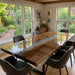 Custom luxury walnut river table used as a high-end office conference table near a window.