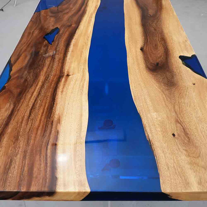 Wooden table with blue resin inlay on a gray floor.