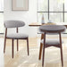 Two gray cushioned chairs with wooden legs in a bright room.