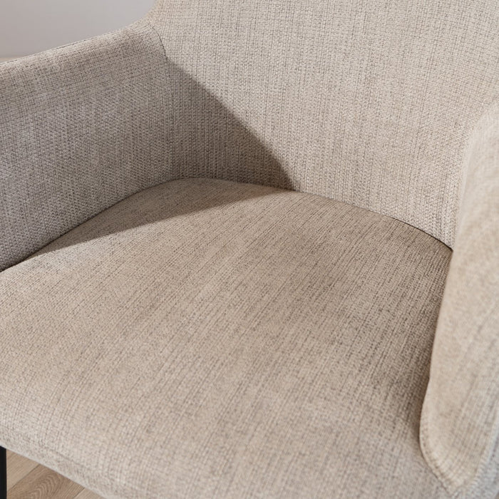 Close-up of a beige upholstered chair with a textured fabric.