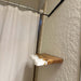 Shower curtain rod with a wooden and white shelf against a textured wall.