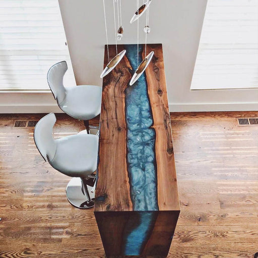 Contemporary live edge bar table with blue epoxy resin river and walnut wood top, paired with modern white stools