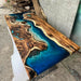 Wooden table with blue resin inlay on a concrete floor