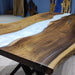 Wooden table with a white resin flow design in a room with blue walls and decorative items.