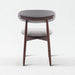 Small round stool with gray cushioned seat and wooden legs on a white background