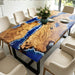 Modern dining table combining camphor wood with ocean-inspired resin wave surface.