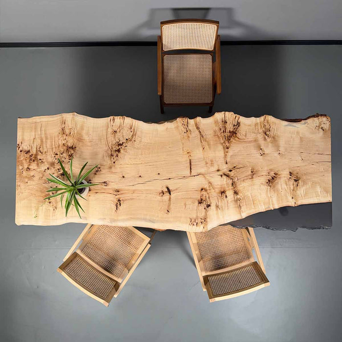 Wooden dining table with natural grain pattern and four chairs on a gray background