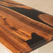 Wooden table with black resin inlay on a light background