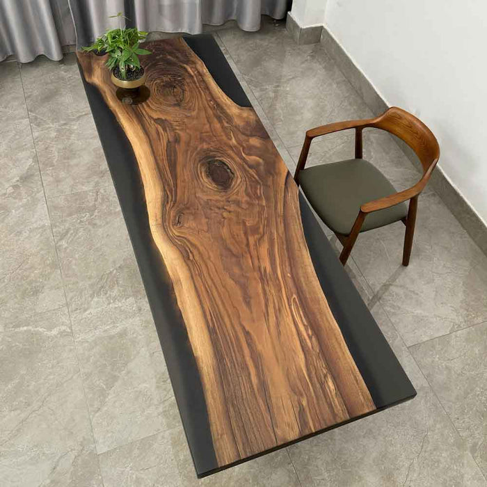 Wooden desk with black base and chair on a tiled floor