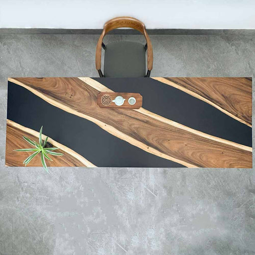 Wooden desk with black surface and decorative elements on a gray floor.