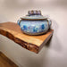 Ceramic pot with blue glaze on a wooden shelf against a plain wall