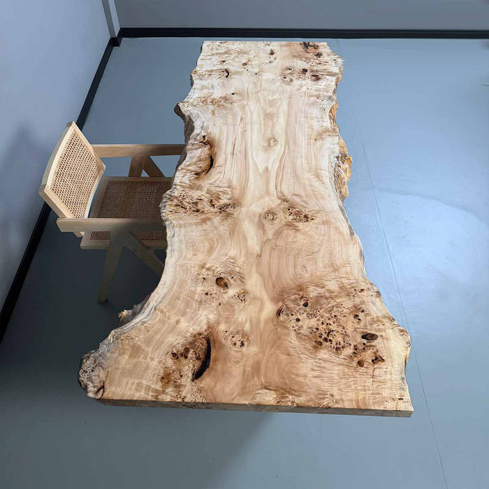 Wooden table with natural grain and a chair in a minimalistic room.