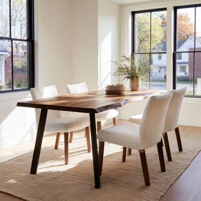 Dining room with a wooden table and white chairs near large windows.