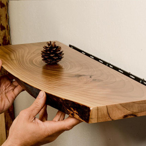 Hand holding a wooden cutting board with a pine cone on a plain background