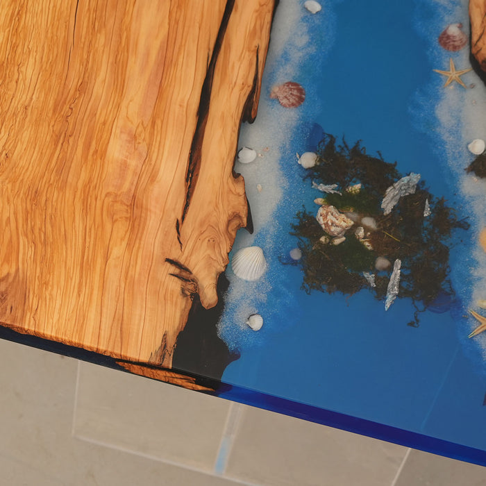 Ocean blue epoxy river table with clear acrylic legs and live edge olive wood