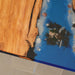 Ocean blue epoxy river table with clear acrylic legs and live edge olive wood